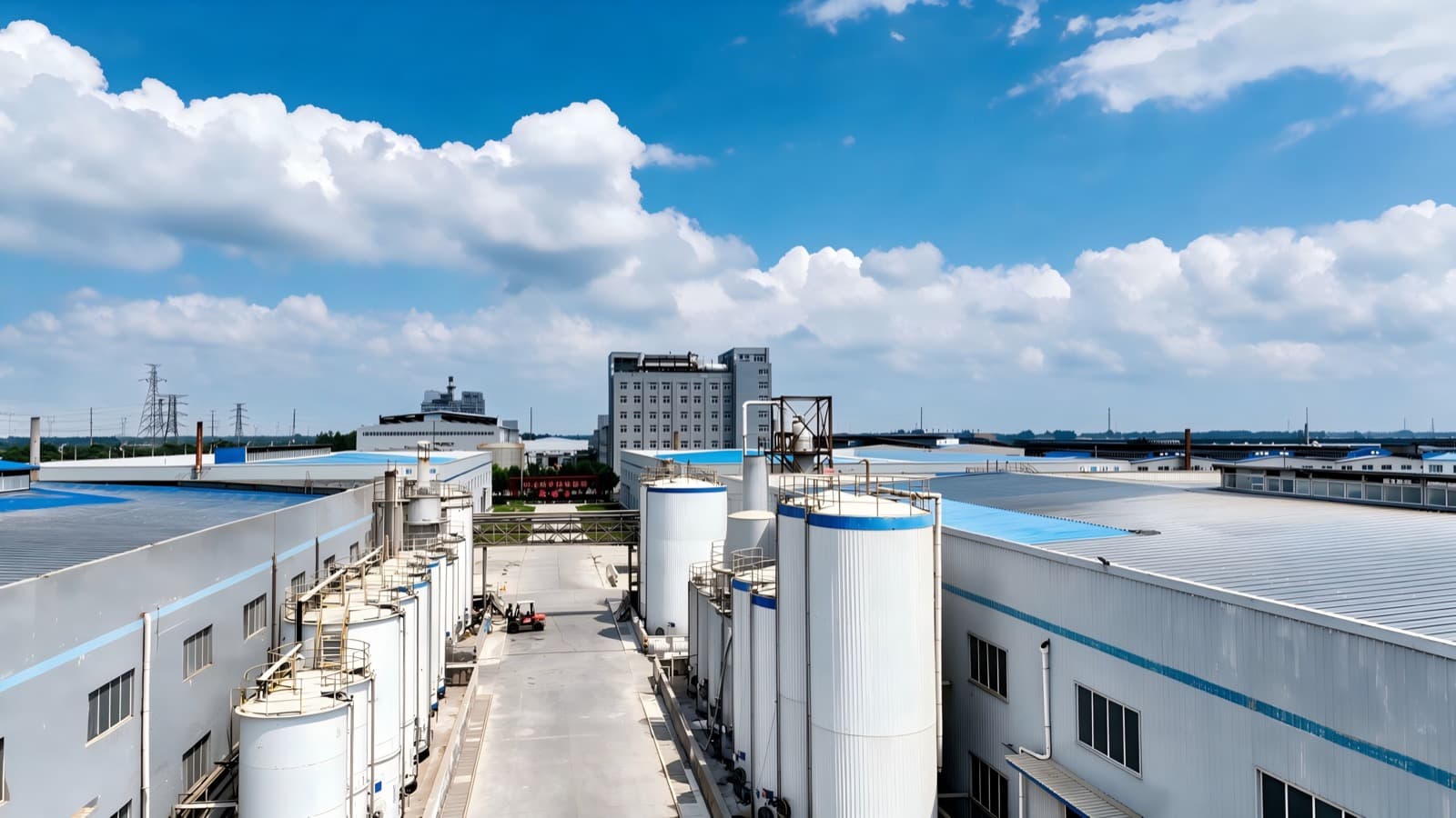 Outdoor storage silos between production workshops at the plant under a blue sky