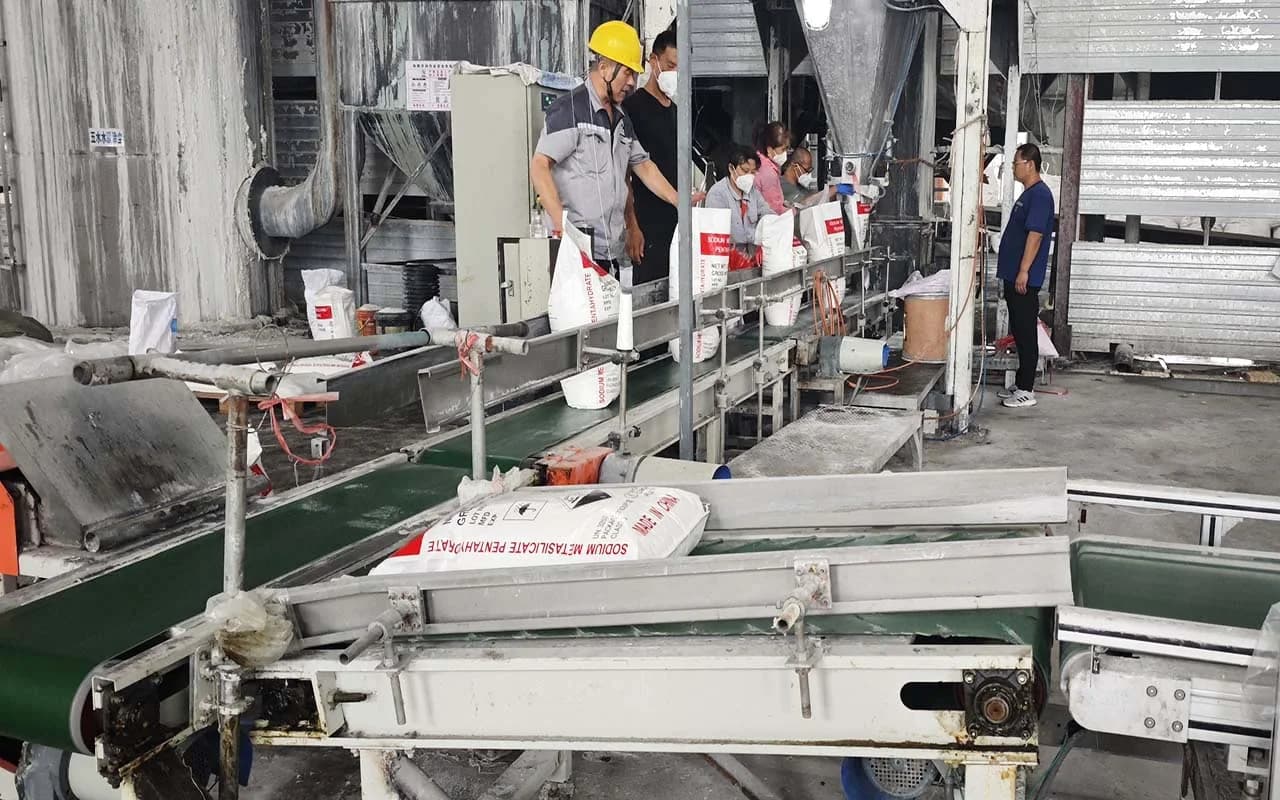 Workers bagging sodium metasilicate pentahydrate on the conveyor packing line
