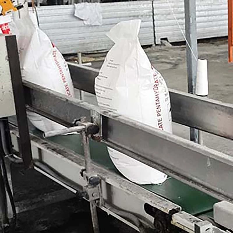 Filled 25 kg sodium metasilicate pentahydrate bags travelling on the conveyor after the bagging station